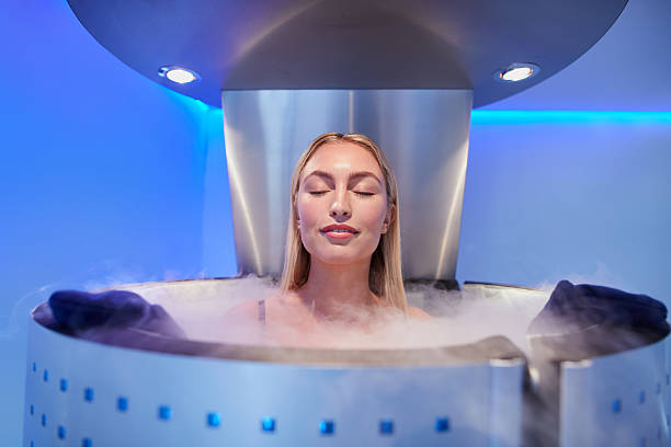 Portrait of happy young woman in a whole body cryotherapy cabin with her eyes closed. Cryosauna chamber for overall increase in muscular performance.